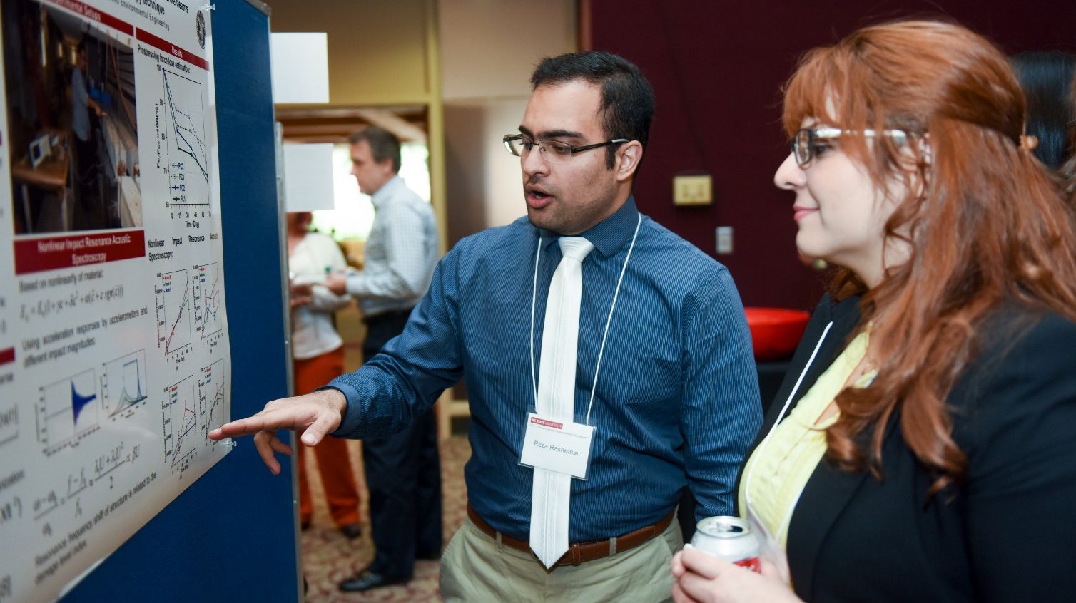 Student stands by research poster