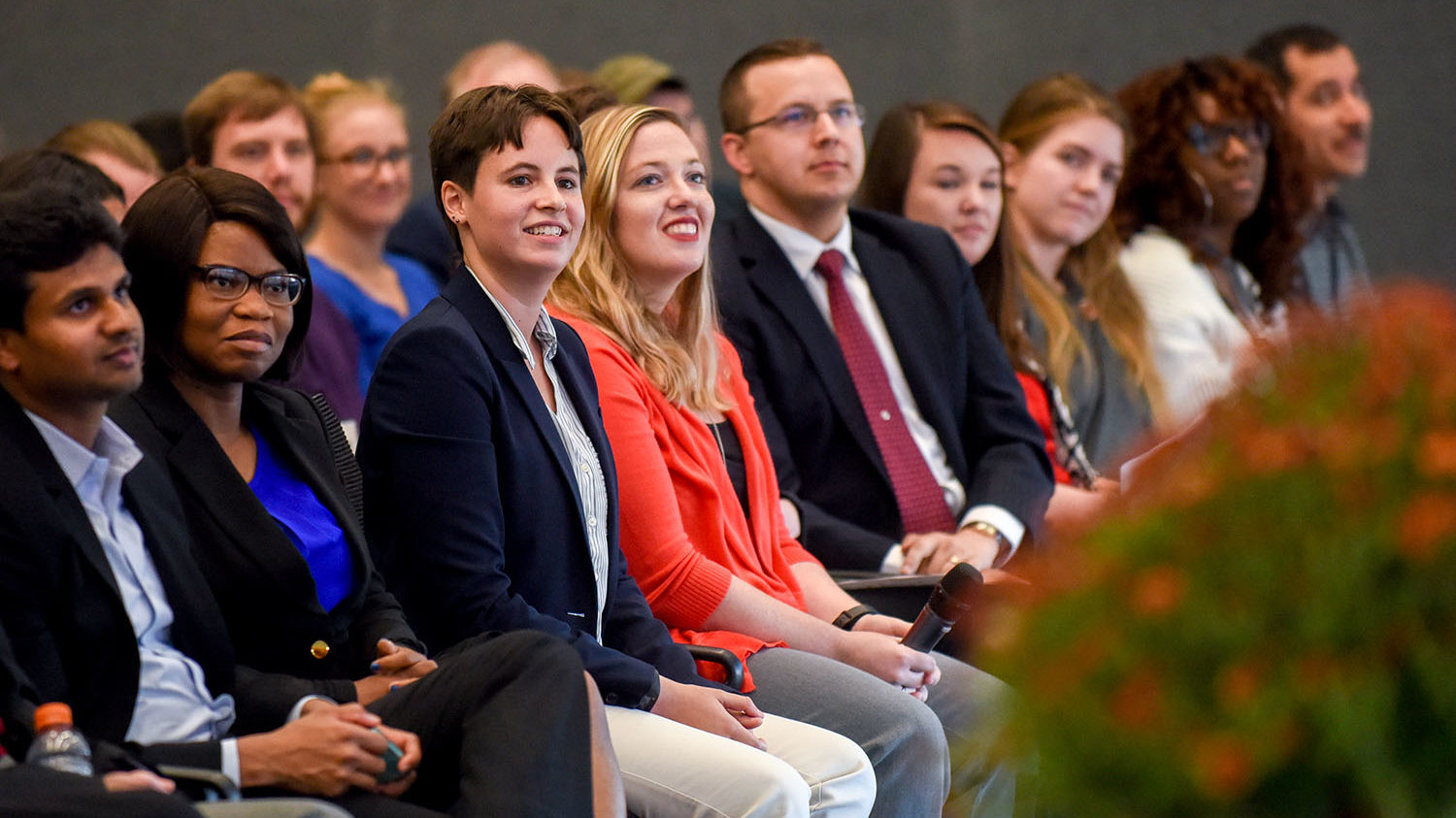 Three minute thesis finalists seated watching another 3 minute thesis presentation.