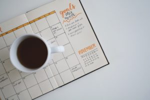 Coffee on top of a planner that has specific goals for the month written