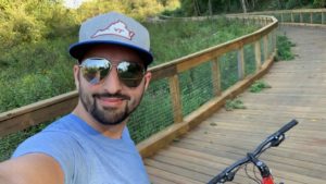 Tim Becker on a bike, smiling at the camera while taking a selfie