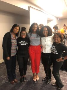 Women of color group standing together at a conference, smiling at the camera