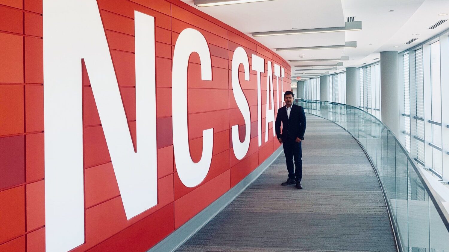 Manik Chandra Biswas standing in front of large NC State sign