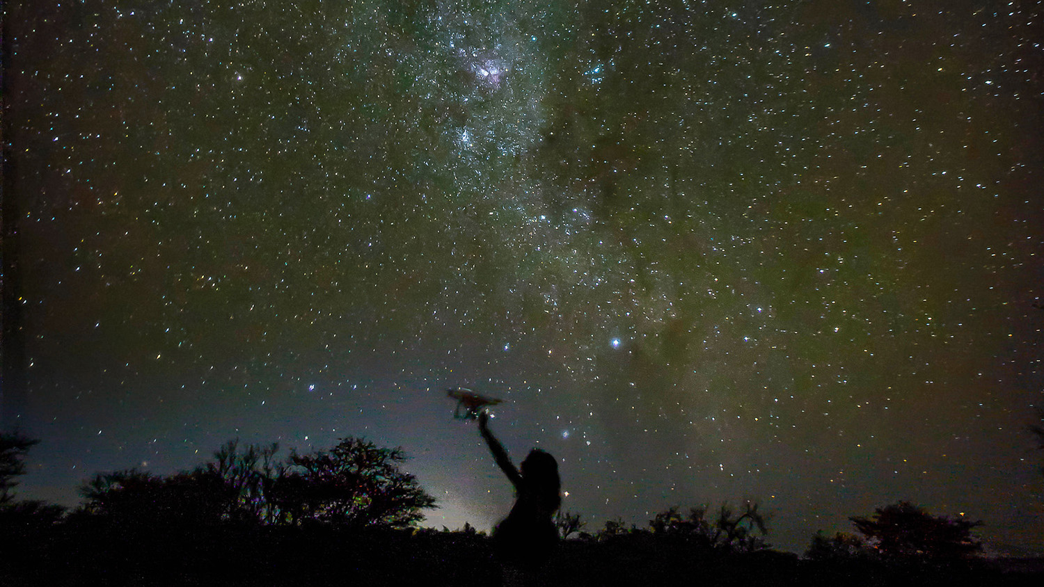 A researchers studying how drones can detect poachers and count wildlife in Namibia is juxtaposed against the Milky Way at night.