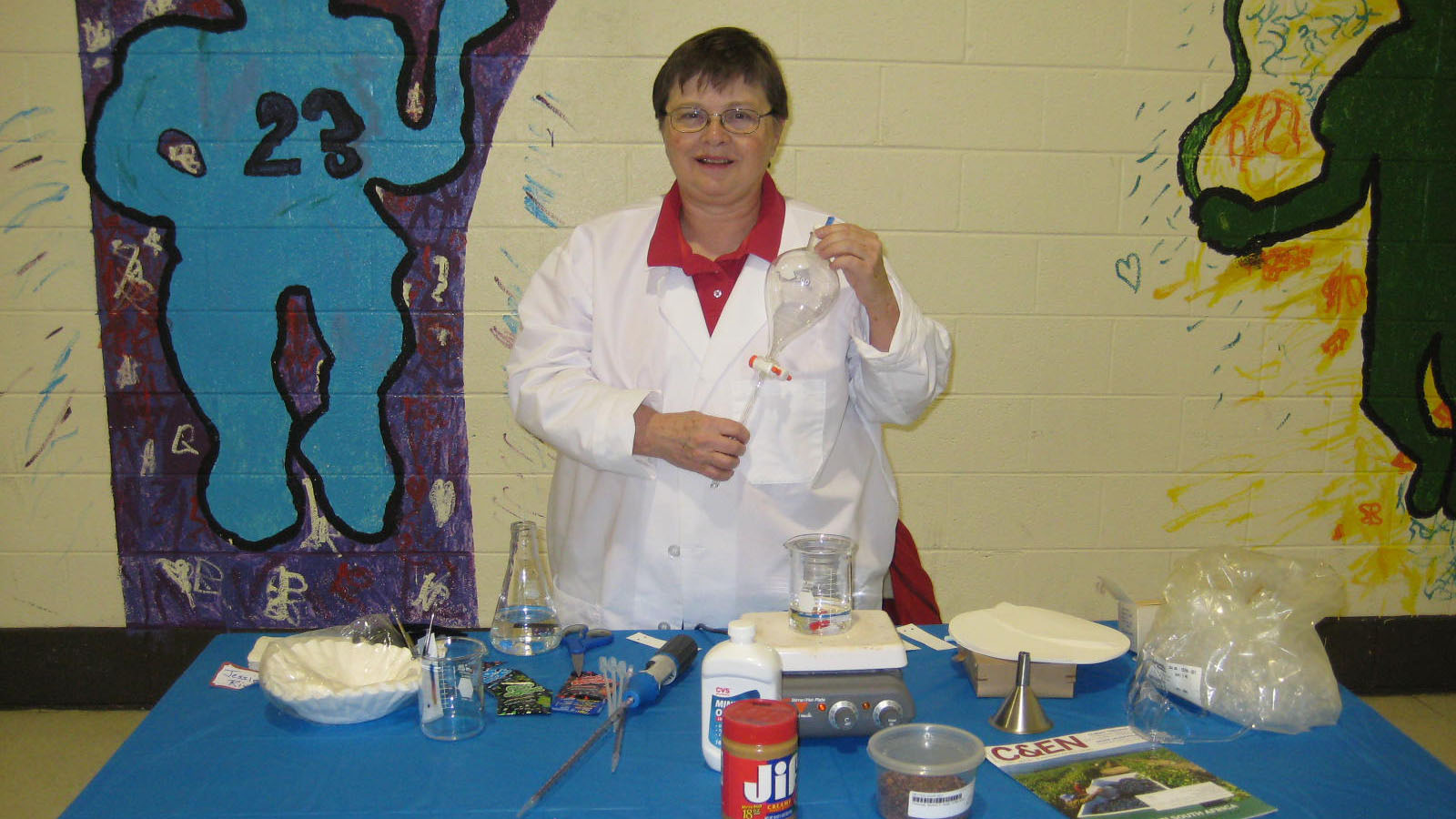 Jessie Rivers stands behind a table at a school career fair, conducting an experiment.