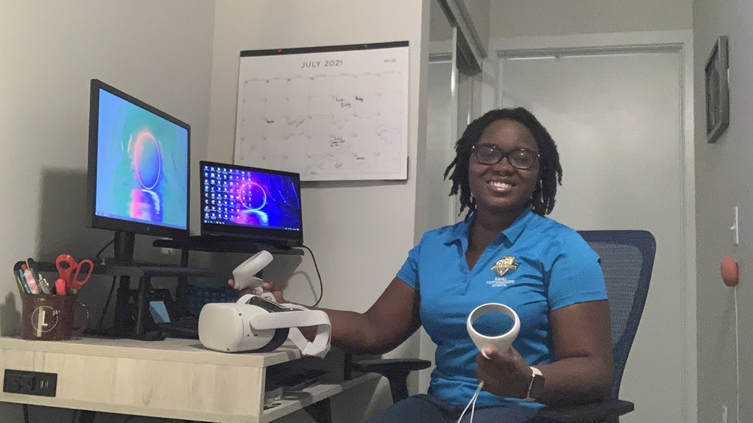 doctoral student holding virtual reality gear while sitting at desk