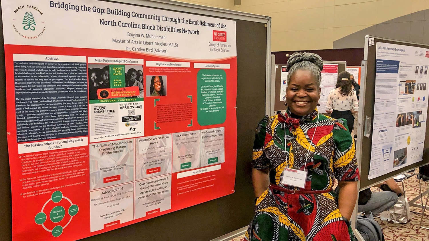 Baiyina Muhammad stands next to her research poster