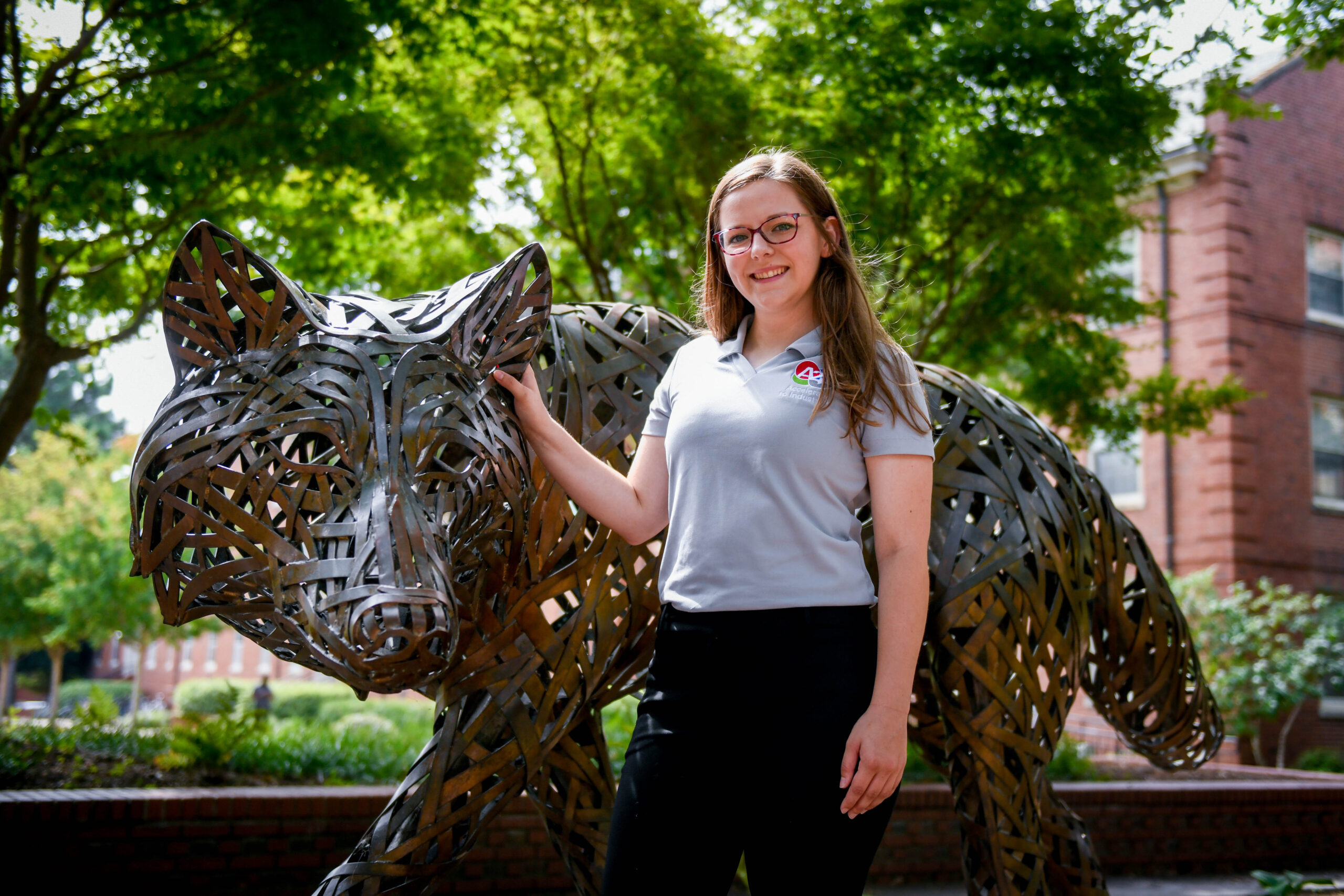 Morgan Dalman standing in front of a copper wolf