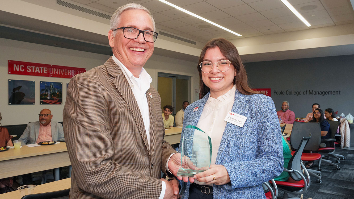 Poole College Dean Frank Buckless gives an award to student Julianna Lopez