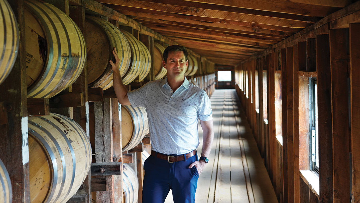 Blake Layfield leans on a bourbon barrel.
