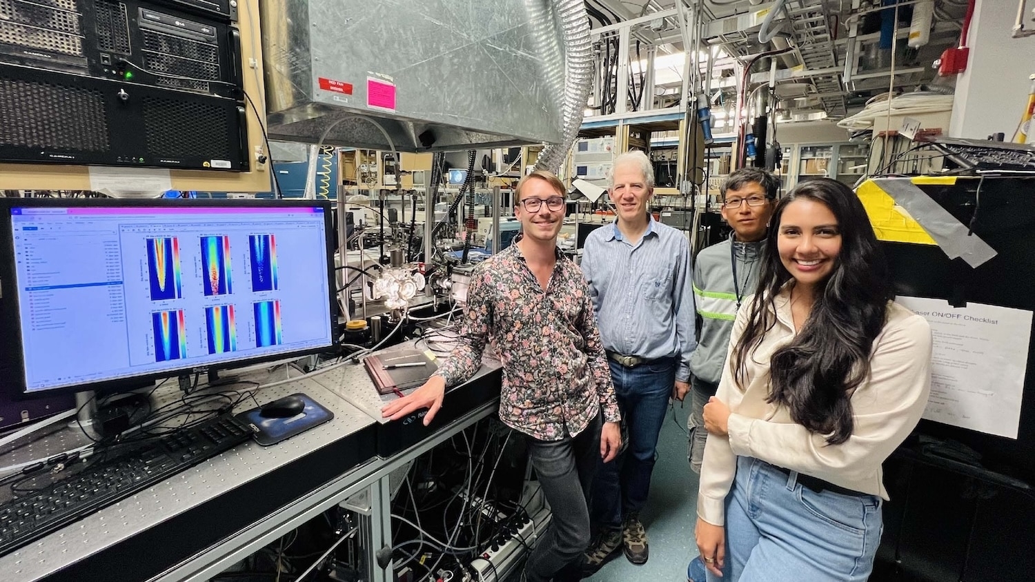 four people standing by a screen showing research images in a national laboratory
